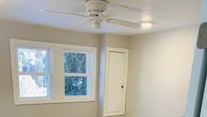 A bedroom with a bed, a ceiling fan, a window, and a door. - Brothers lake drive chalet (Shawano)