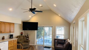 A spacious living area with a dining table, a sofa, a ceiling fan, and a television mounted on the wall. - Brothers lake drive chalet (Shawano)