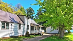 A two-story house with a porch and a garage. - Brothers lake drive chalet (Shawano)