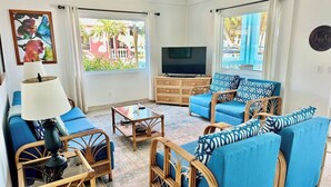 Ein Wohnzimmer mit blauen Sofas, einem Fernseher und einem Deckenventilator.