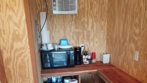 A compact kitchen with a microwave, coffee maker, and storage shelves. - Little Cabin at the DonkeyRanch (Lawton)