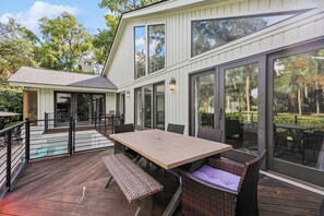 A modern house with a deck, outdoor furniture, and large windows.