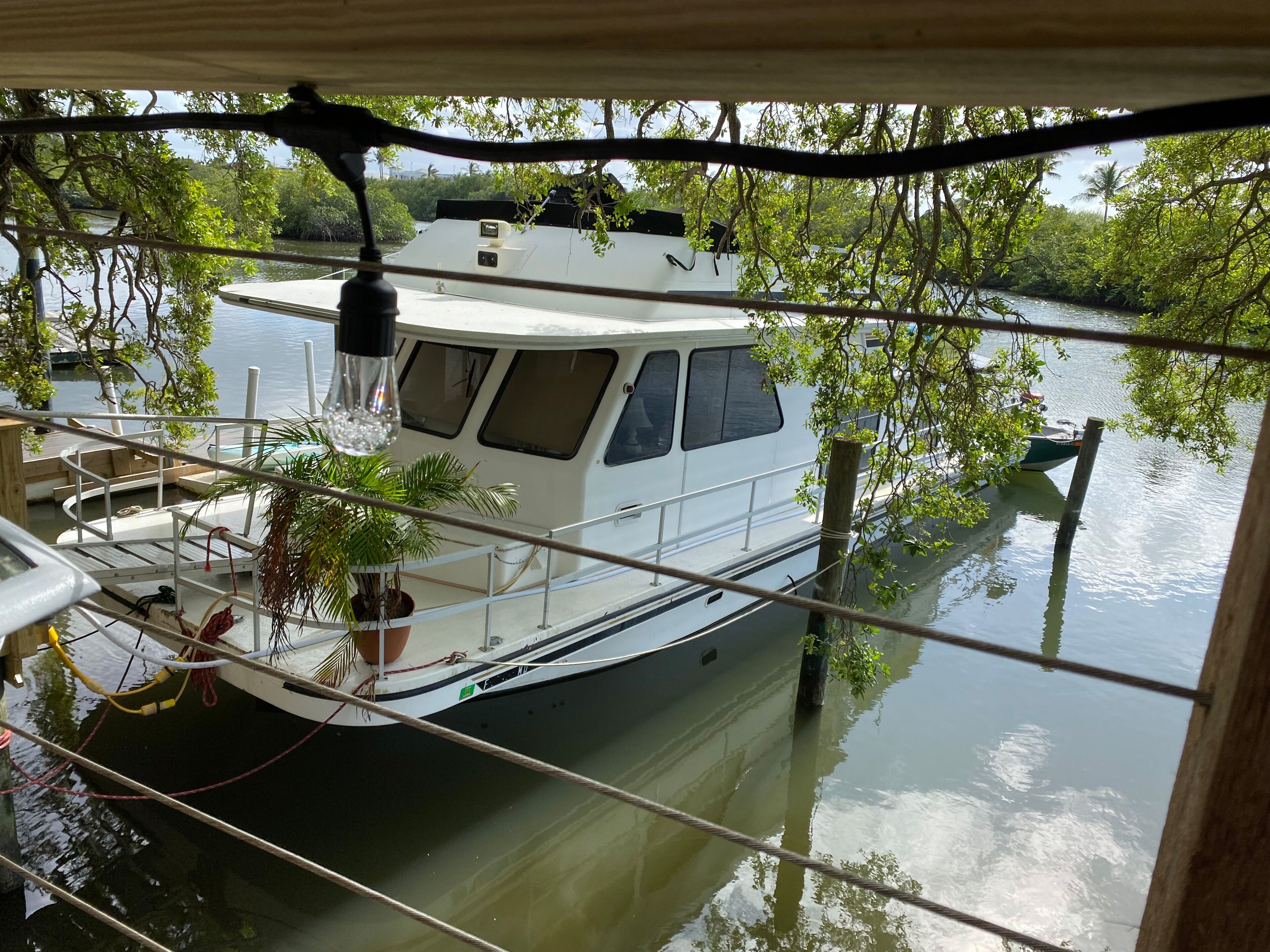 Un bateau était amarré à un quai, muni d’une rambarde, d’un pot de fleurs et d’un luminaire placé au-dessus.
