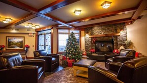 A cozy living room with leather sofas, a Christmas tree, and a stone fireplace. - Lux Blackstone Mountain Suite with Amazing Views (Canmore)