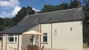 Une maison dotée d’un patio comprenant une table et des chaises, une petite fenêtre et une cheminée.