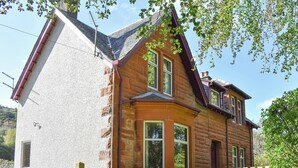 Une maison à deux étages avec une façade en pierre et une extension en bois.