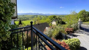 Uma varanda com vista para uma paisagem verde e montanhas ao longe.