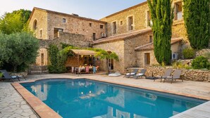 Ein Steingebäude mit Pool, Sitzmöglichkeiten im Freien und einer Pergola.