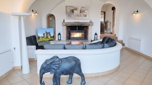 Ein modernes Wohnzimmer mit einer gebogenen weißen Couch, einem Kamin und einer großen Elefantenstatue.