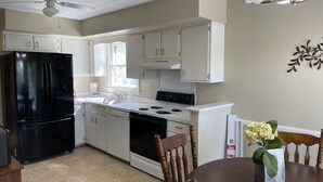 A modern kitchen with white cabinets, a black refrigerator, a stove, and a dining table with chairs. - Spread out and chill!  Close to shop and eateries and 1 mile expressway (Louisville)