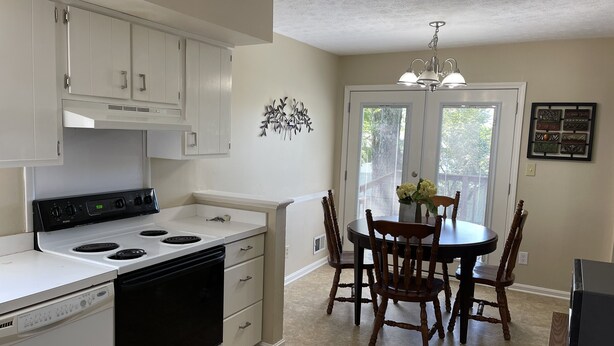 A kitchen with white cabinets, a stove, and a dining table with chairs. - Spread out and chill!  Close to shop and eateries and 1 mile expressway (Louisville)
