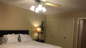 A hotel room with a bed, a nightstand with a lamp, a ceiling fan, and a door. - Spread out and chill!  Close to shop and eateries and 1 mile expressway (Louisville)