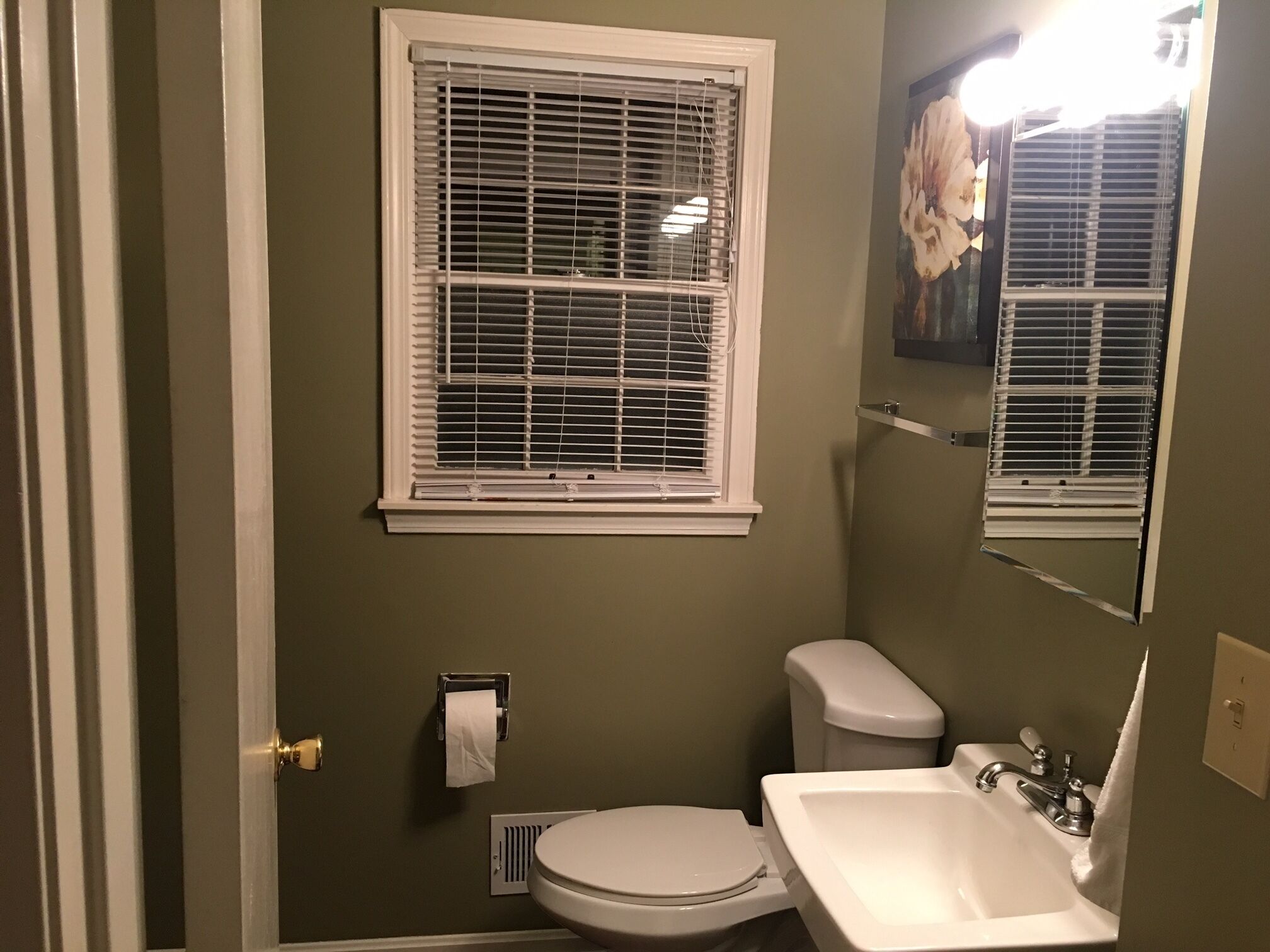 A bathroom with a toilet, sink, and window with blinds.