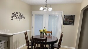 A dining area with a round table, four wooden chairs, a vase with flowers, and a chandelier. - Spread out and chill!  Close to shop and eateries and 1 mile expressway (Louisville)