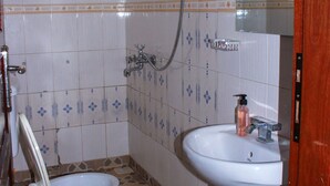 Un bagno con il water, lavandino e doccia.