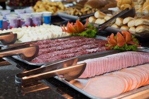 A buffet with various meats and cheeses.