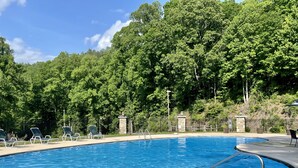 Una piscina con sillones de descanso y un pilar de piedra.
