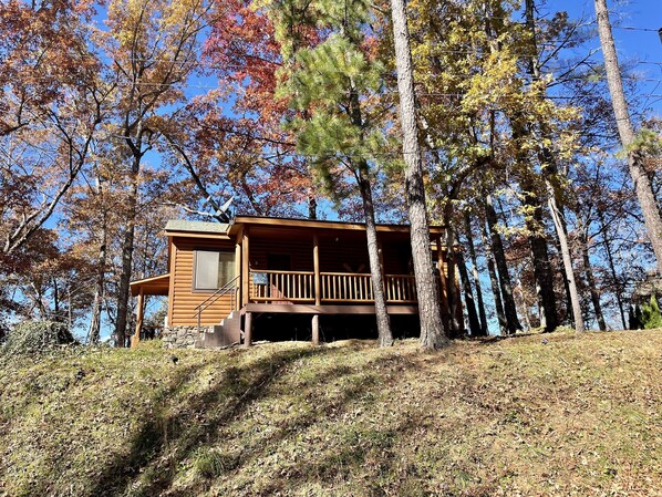 A cabin with a wooden exterior, a balcony, and a stone staircase leading up to it.