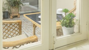 A view through a window of a room with a small table, chairs, and potted plants. - Zarco B&B - Bed and Breakfast (Funchal)