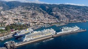 A coastal city with a large cruise ship docked at a pier, surrounded by residential buildings and mountains in the background. - Zarco B&B - Bed and Breakfast (Funchal)