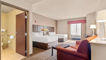 A hotel room with a bed, two bedside tables, a desk, a chair, a bathroom with a toilet and towel rack, and a window with curtains.
