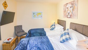 A hotel room with two beds, a chair, a map on the wall, and a TV mounted on the wall.