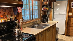 A kitchen with wooden cabinets, a stove, a sink, and a washing machine.