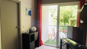 Et værelse med en skydedør til en balkon, et lille skrivebord med lampe, og et billede på væggen.