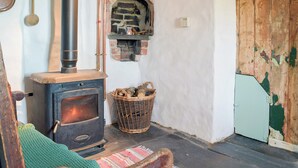 Une pièce rustique avec un poêle à bois, un four en briques et une porte en bois.