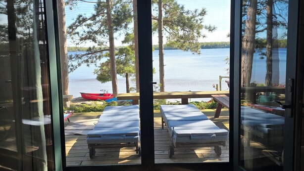 A room with a view of a lake, outdoor seating, and a boat dock.