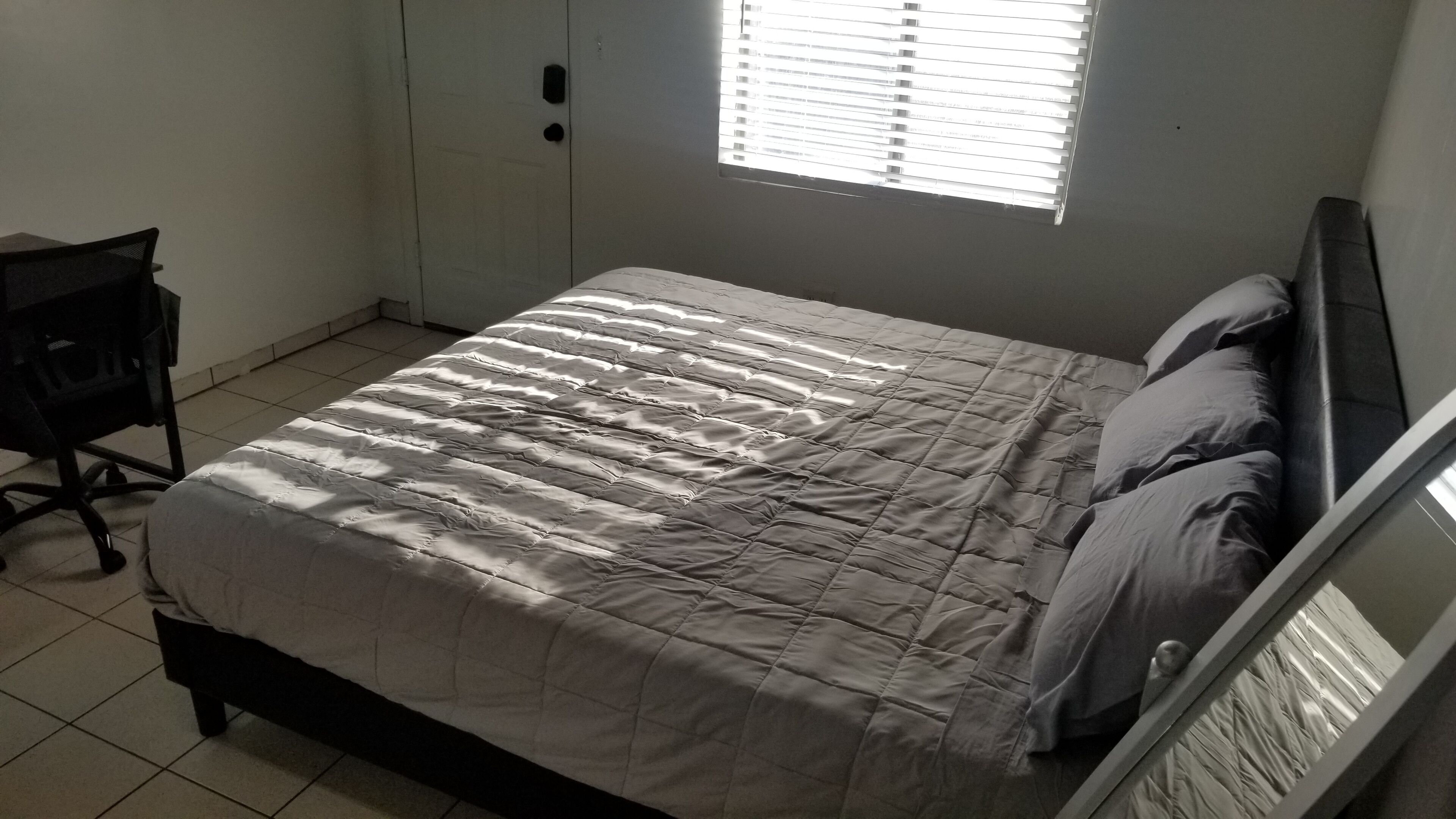 A bedroom with a bed, a desk, and a window.