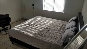 A bedroom with a bed, a desk, and a window.