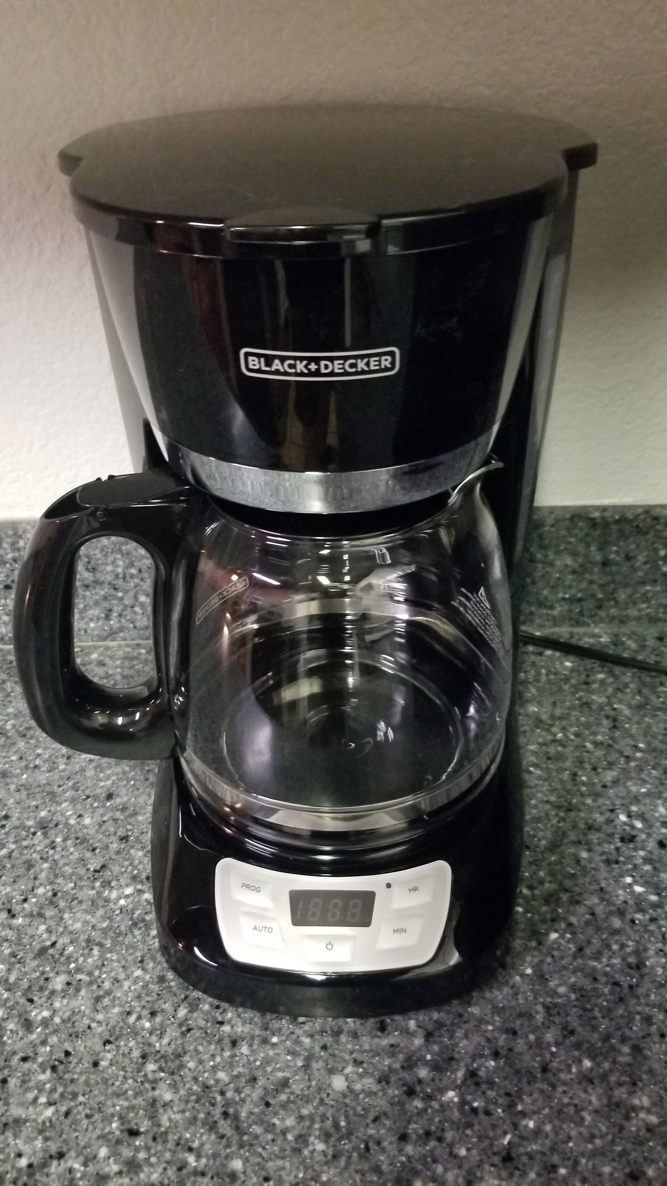 A BLACK+DECKER coffee maker with a digital display on a granite countertop.