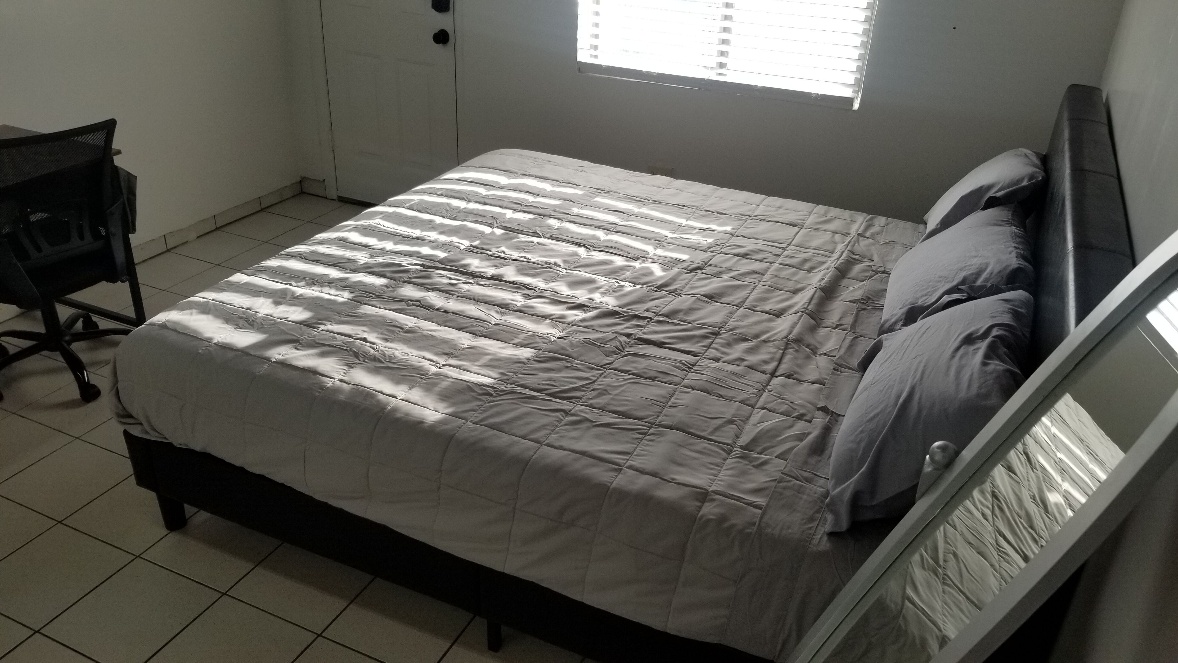 A bedroom with a bed, a chair, and a window.