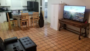 Un espacio habitable compacto con cocina, comedor y televisor sobre un soporte de madera.