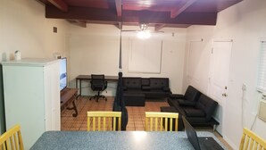 Una sala de estar con sofá, sillas, una mesa de comedor y televisor.