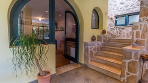 Un vestíbulo con un gran arco que da a un comedor, una escalera de piedra y una planta en maceta.