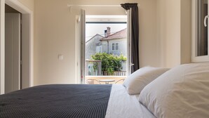 A hotel room with a bed, a balcony with a view of buildings and greenery, and a window with curtains. - Villa Lali - Modern Villa near the sea in Lukoran (Lukoran)