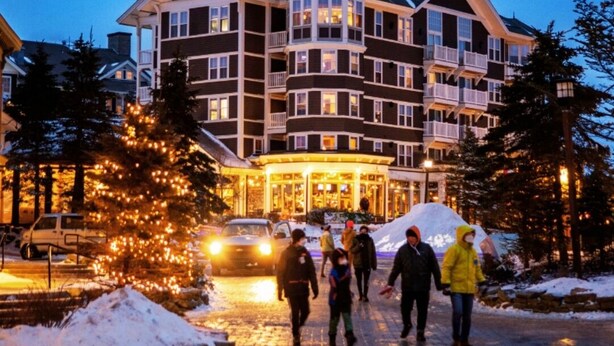 Ein mehrstöckiges Hotel mit einem zentralen Turm, Balkonen und einer verschneiten Auffahrt.