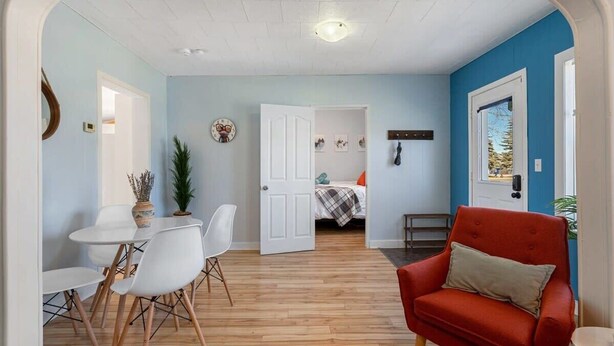 Une pièce comprenant un coin repas, une chaise rouge et un lit avec un mur bleu.
