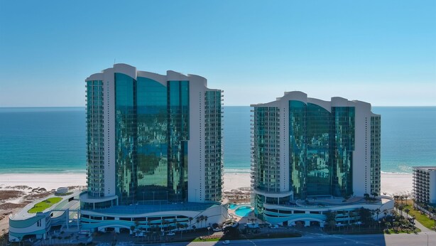 Twin high-rise hotels with a beach view, featuring a pool and a beach area.