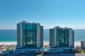 Twin high-rise hotels with a beach view, featuring a pool and a beach area.
