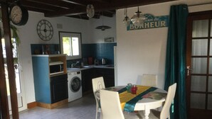 A kitchen with a washing machine, a dining table with chairs, and a sign that reads "Maison du BONHEUR". - Villa familiale dans grand jardin arboré à 200 m de la plage et proche village.. (Saint-Gildas-de-Rhuys)