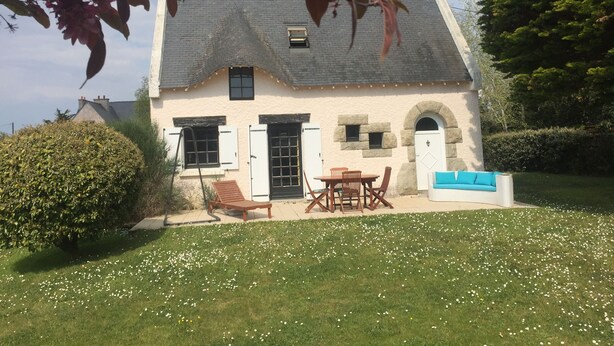 A house with a stone facade, a thatched roof, and a small garden with a lawn and white flowers. - Villa familiale dans grand jardin arboré à 200 m de la plage et proche village.. (Saint-Gildas-de-Rhuys)