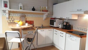 A compact kitchen with white cabinets, a microwave, a coffee maker, and a sink. - Gîte T2 Aspres (Tautavel)