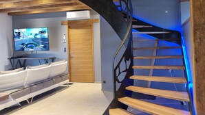 A modern interior with a wooden staircase, a flat-screen TV, and a seating area. - La Grange 🌿 (Le Bugue)