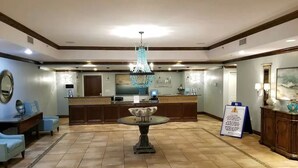 A lobby with a reception desk, a chandelier, a dining table, and a sign. - 2 bedroom, gulf facing master en suite.  Includes 2 seasonal beach chairs. (Panama City Beach)