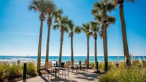 A beachside patio with palm trees, outdoor seating, and a view of the ocean. - 2 bedroom, gulf facing master en suite.  Includes 2 seasonal beach chairs. (Panama City Beach)