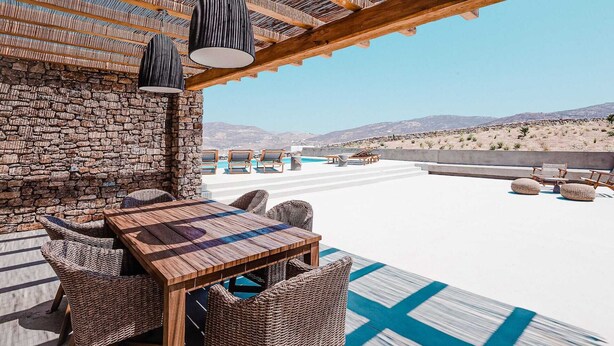 A rooftop terrace with a stone wall, wicker furniture, and a view of the desert landscape. - Two Bedroom Suite  with Private Pool (Mykonos)
