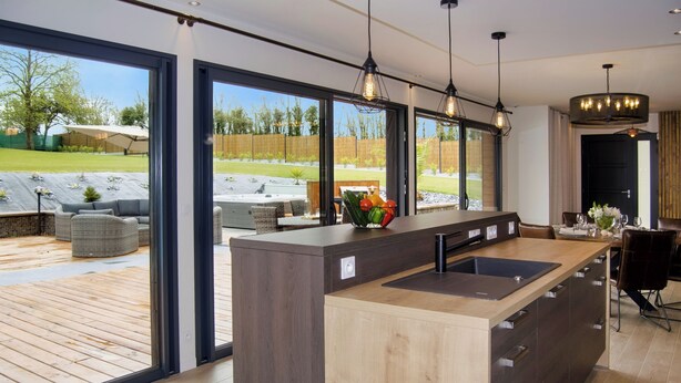 A modern kitchen with a large island, built-in appliances, and a view of the backyard. - Villa Cosy, Pool, Spa, Relaxation Area (Sauna & Hammam) 8 km from the beaches! (Pordic)